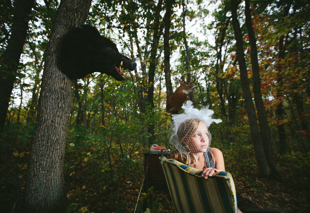 Teslyn in woods with boar mount and deer mount wearing birdcage vail