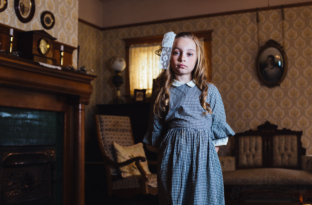 Teslyn posing in early 1900s living room by fireplace