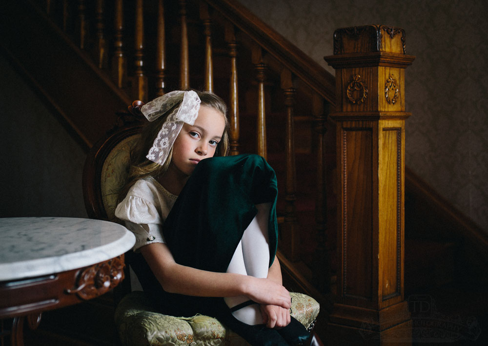 Teslyn sitting in antique chair with her knees up