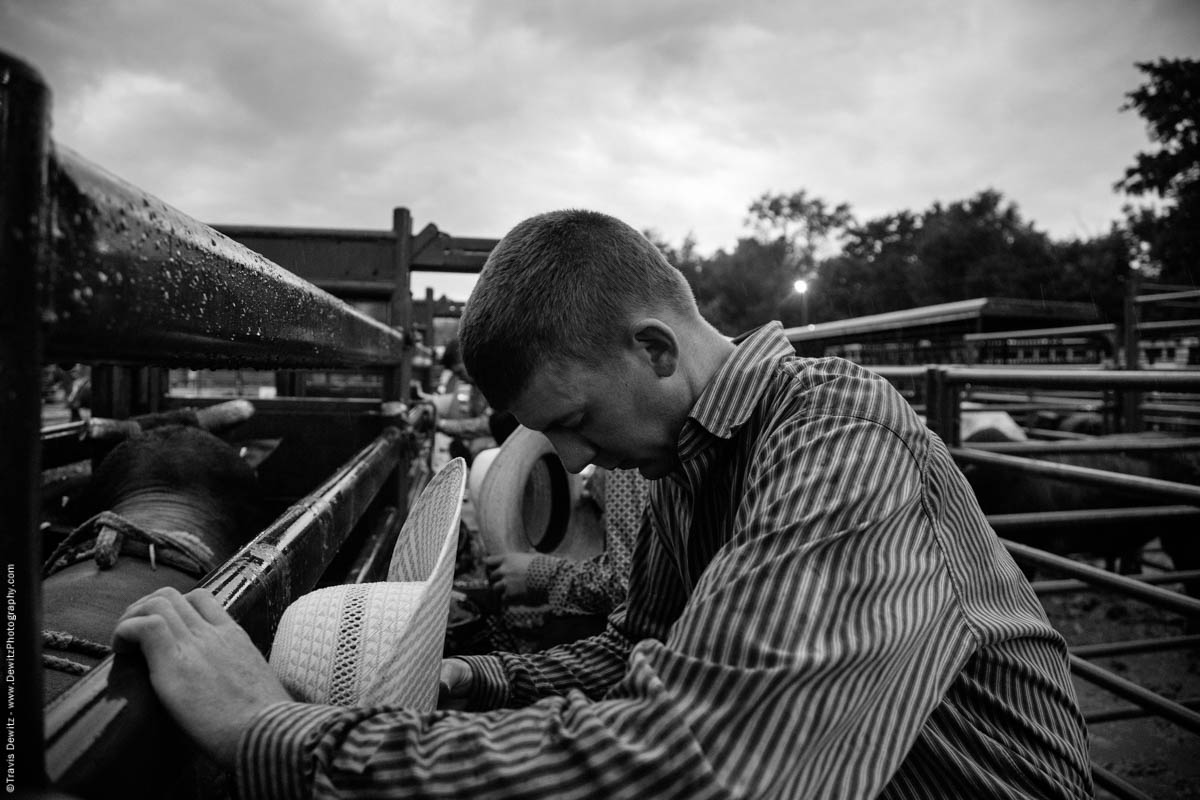 bull-rider-prays-before-rodeo-cowboy-hat-off-western-shirt-behind-the-chutes-in-the-rain-4611